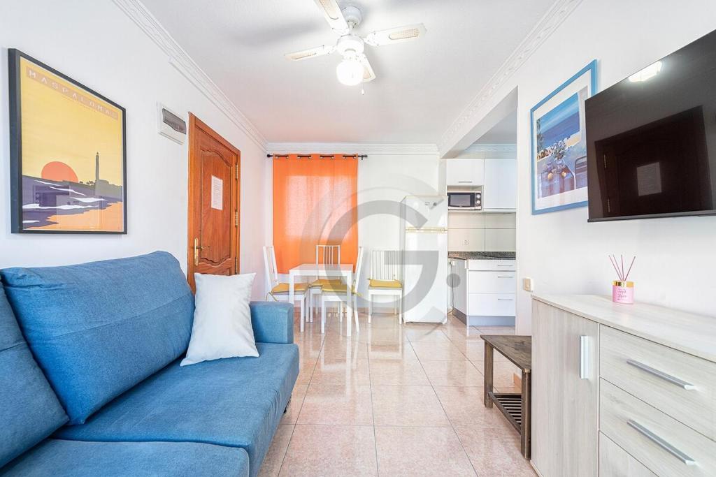 Una sala de estar con un sofá azul y una mesa. en San Agustin Ocean View, en Maspalomas