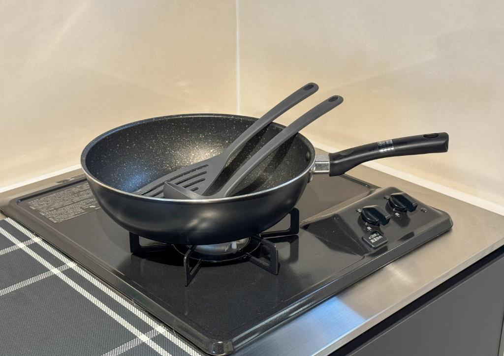 a pan sitting on top of a stove with tongs at 良居民宿 YOSHII House 晴空塔徒步圈 整栋出租 in Tokyo