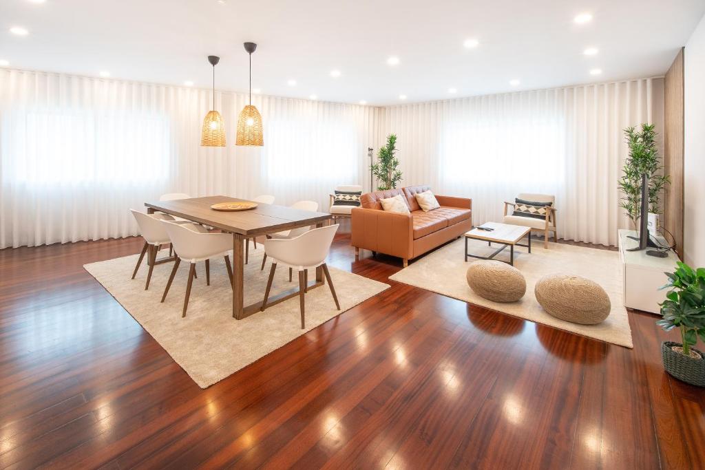 a dining room and living room with a table and chairs at Costa Nova Premium Apartment & Pool in Costa Nova