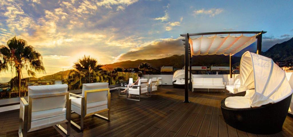 une terrasse avec des chaises blanches et un kiosque dans l'établissement Acogedor Apartamento con Piscina y Jardin, à Los Llanos de Aridane