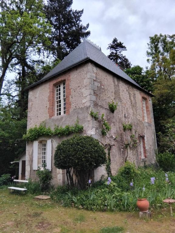 an old brick building with flowers in front of it at La Tour Des Douves in La Celle-sous-Gouzon