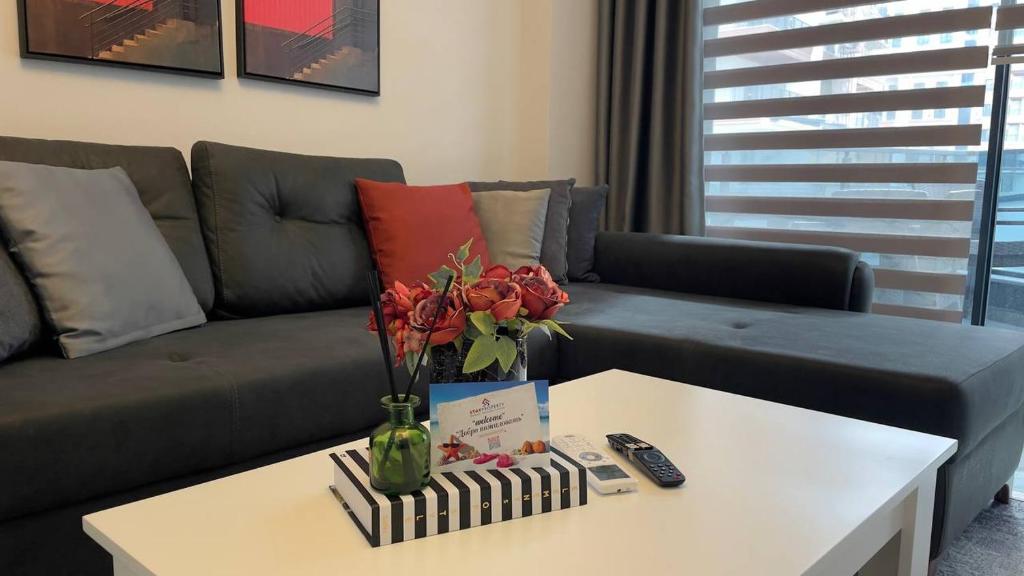 a living room with a couch and a table with flowers at 0017 White Sail Cozy 1-Bedroom Apartment Steps from Yekta Mall in Mahmutlar, Alanya in Alanya