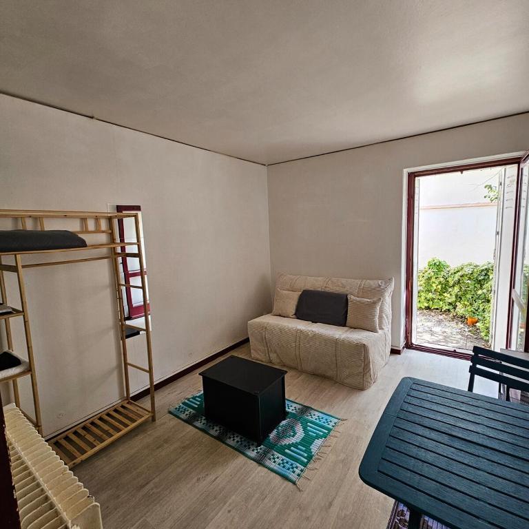 un salon avec un canapé et une fenêtre dans l'établissement Studio calme avec petit jardinet, à Bordeaux