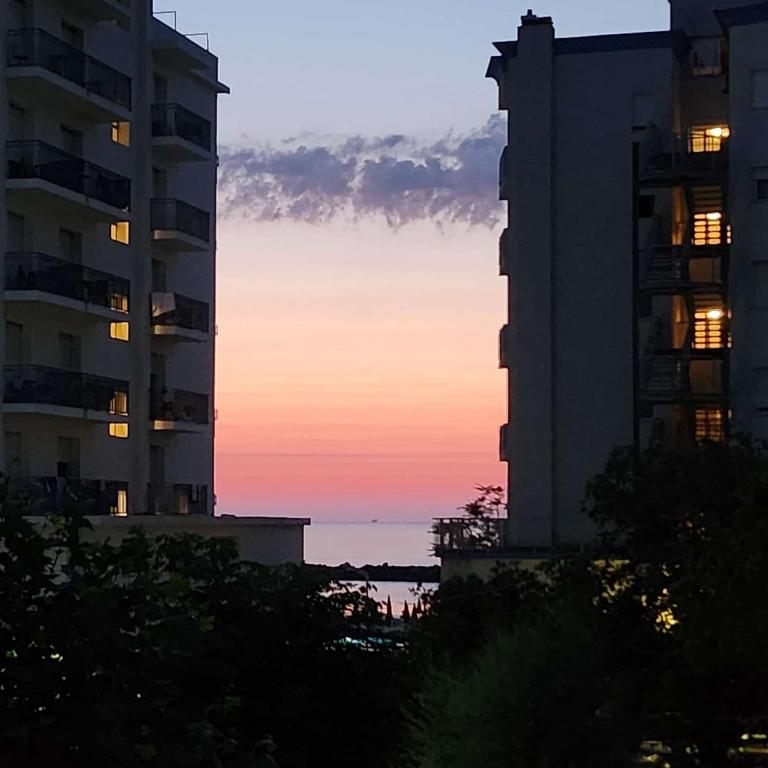 two tall buildings with the sunset in the background at Appartamento Gina lido di savio in Lido di Savio