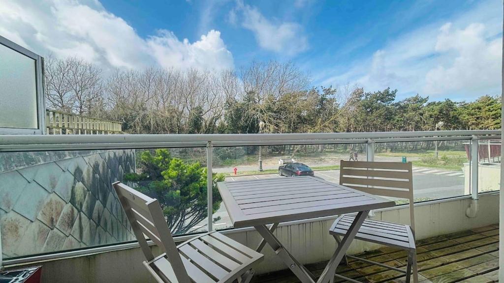 une table en bois et deux chaises sur un balcon dans l'établissement Appart T3 pinède 5 min de la plage, à Le Touquet-Paris-Plage