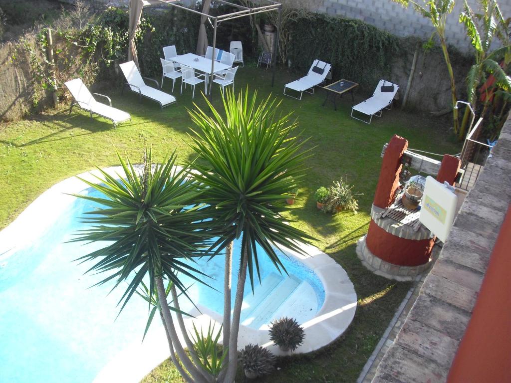 uma piscina com cadeiras, uma mesa e uma palmeira em La Posada de Menchu em Sanlúcar de Barrameda