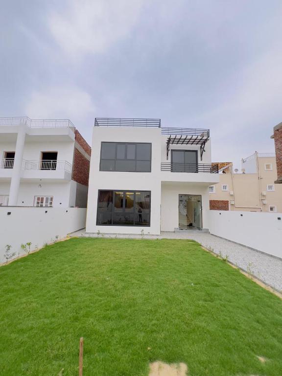 una casa blanca con un césped verde delante de ella en Villa Kayan, en Luxor