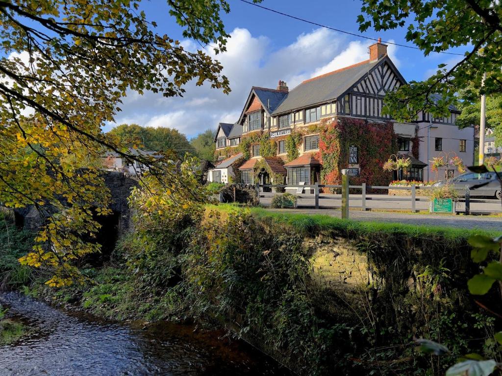a large house with a river in front of it at Exmoor White Horse Inn in Exford