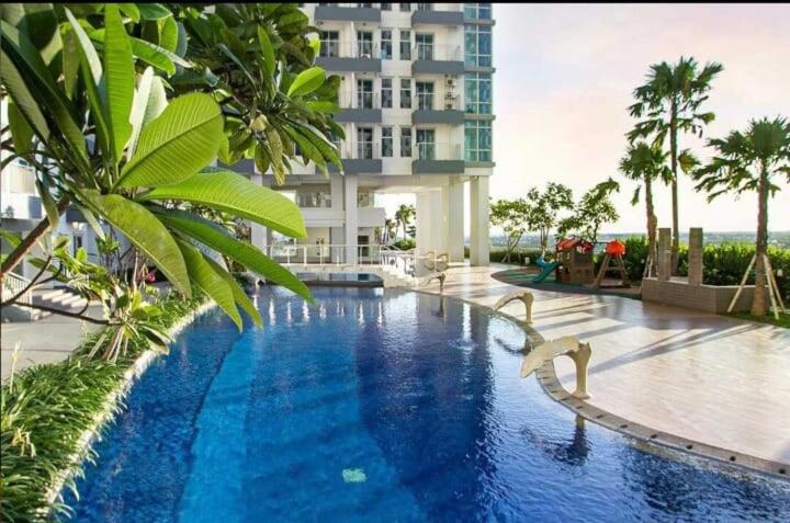 a swimming pool in front of a large building at LuxBedAndersonPakuwon by BnB in Surabaya