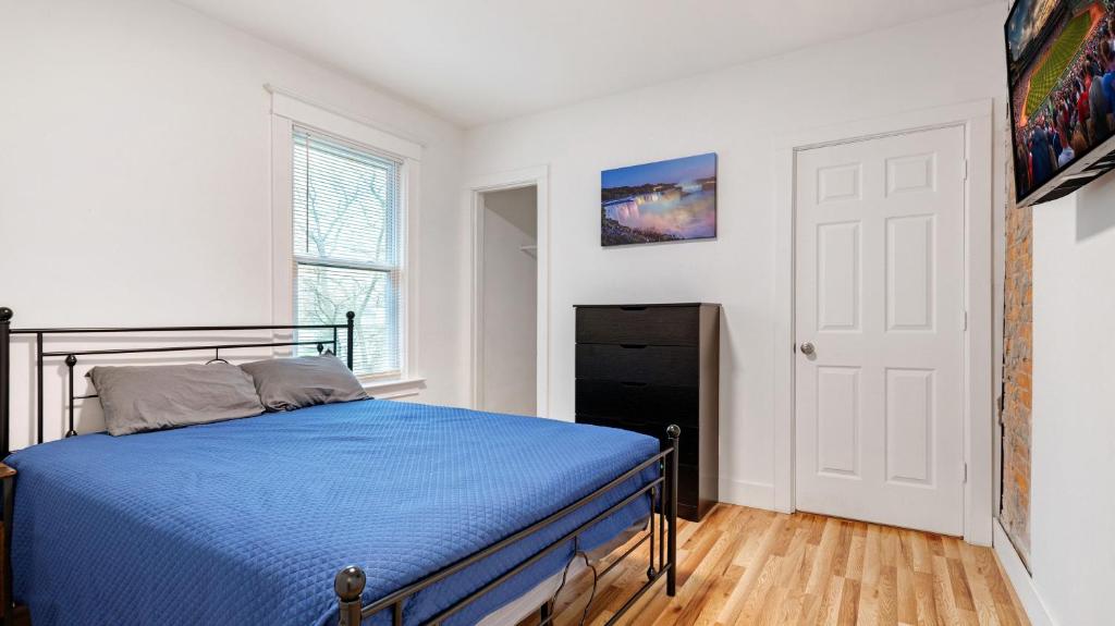 a bedroom with a blue bed in a white room at 6 bedroom House Short Walk to Niagara Falls in Niagara Falls