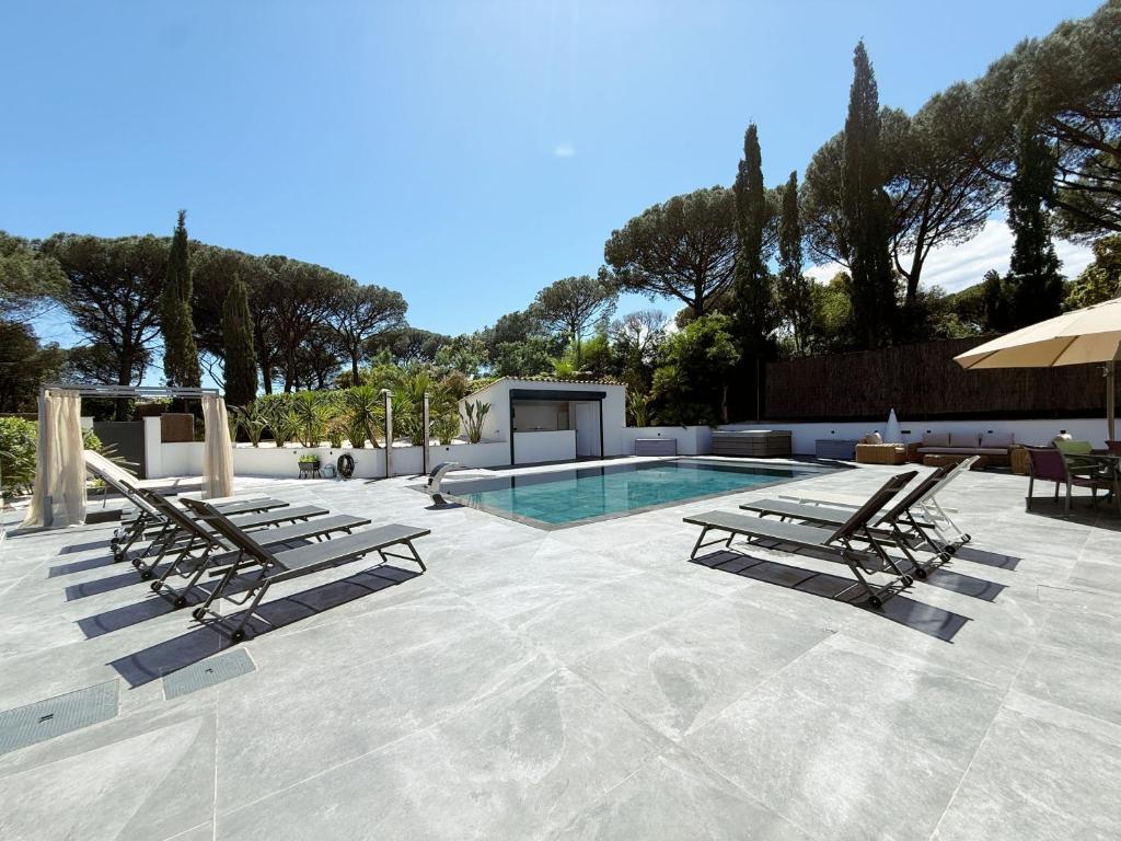 - une piscine avec 2 chaises longues et un parasol dans l'établissement Villa les Cépèdes, à Sainte-Maxime