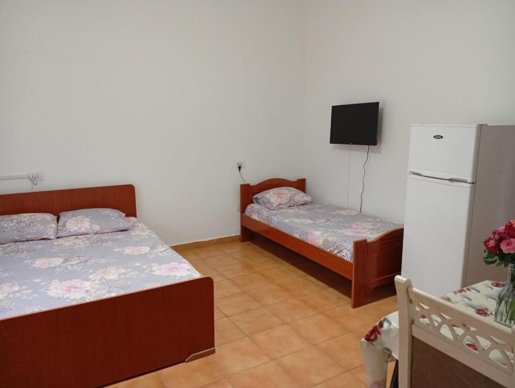 a room with two beds and a refrigerator and a tv at Arta room in Durrës