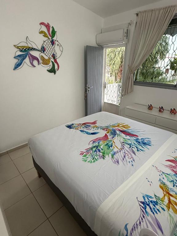 a bedroom with a bed with a painting on it at COMME un POISSON in Sainte-Anne