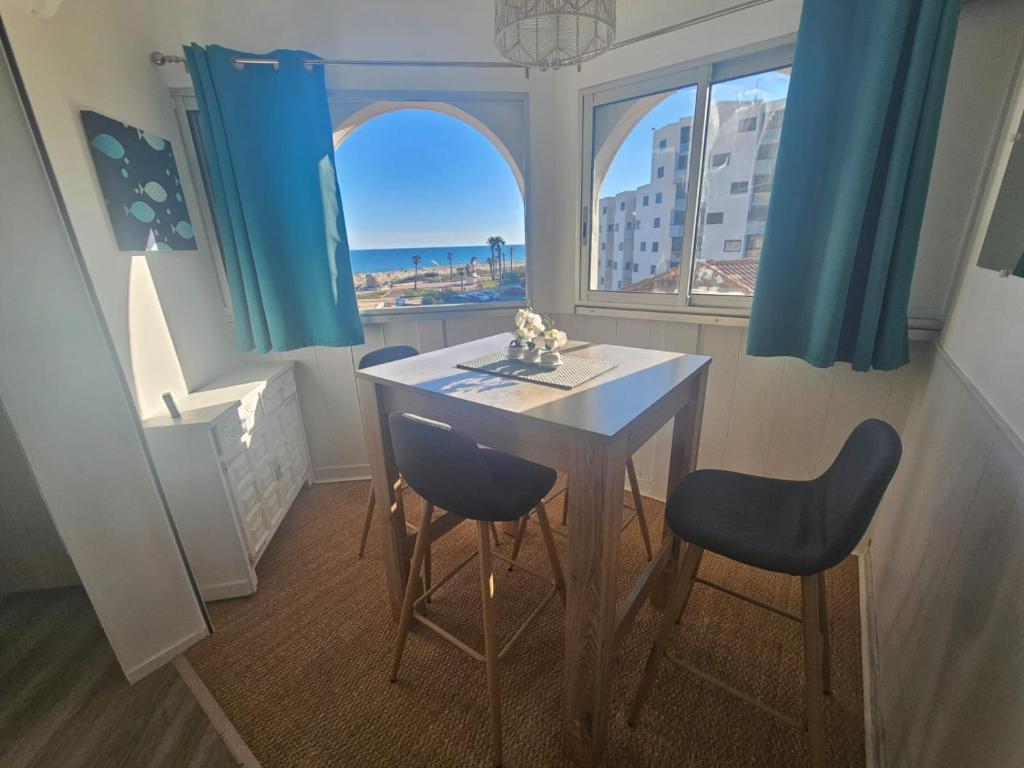 d'une salle à manger avec une table, deux chaises et une fenêtre. dans l'établissement Le Cocon de Julie, au Barcarès