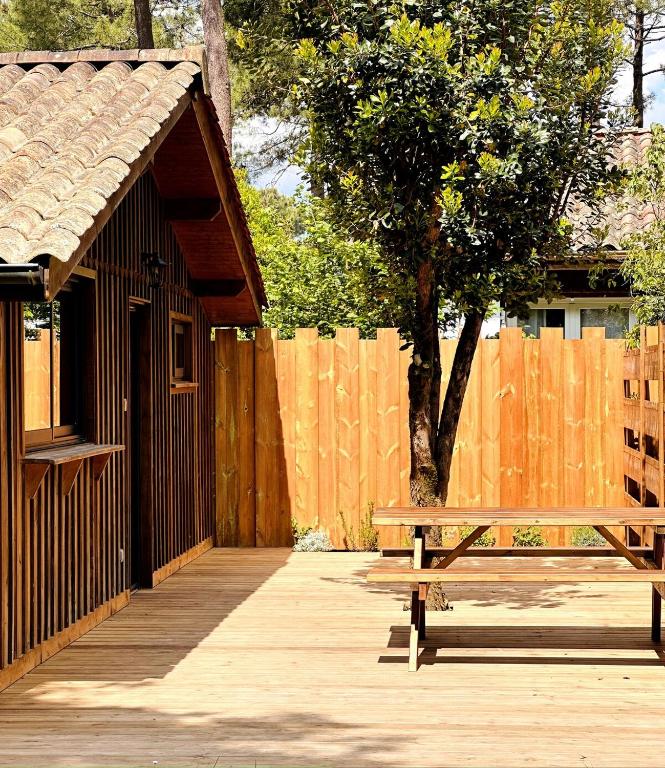 un banc en bois assis à côté d'une clôture en bois dans l'établissement Cabin, terrace and enclosed garden, à Lanton