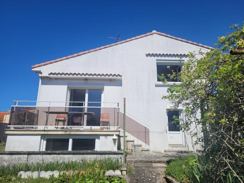 une maison blanche avec des chaises rouges sur le balcon dans l'établissement Maison calme à un 15min à pied de la plage, à Royan