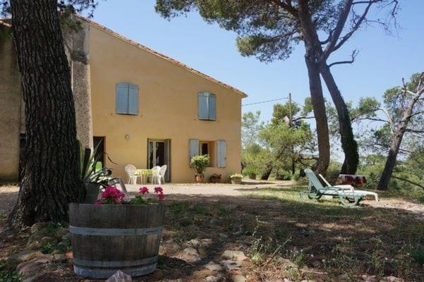 une grande maison jaune avec une table et des chaises dans une cour dans l'établissement Gîte sur un domaine viticole en agriculture biologique, à Cessenon