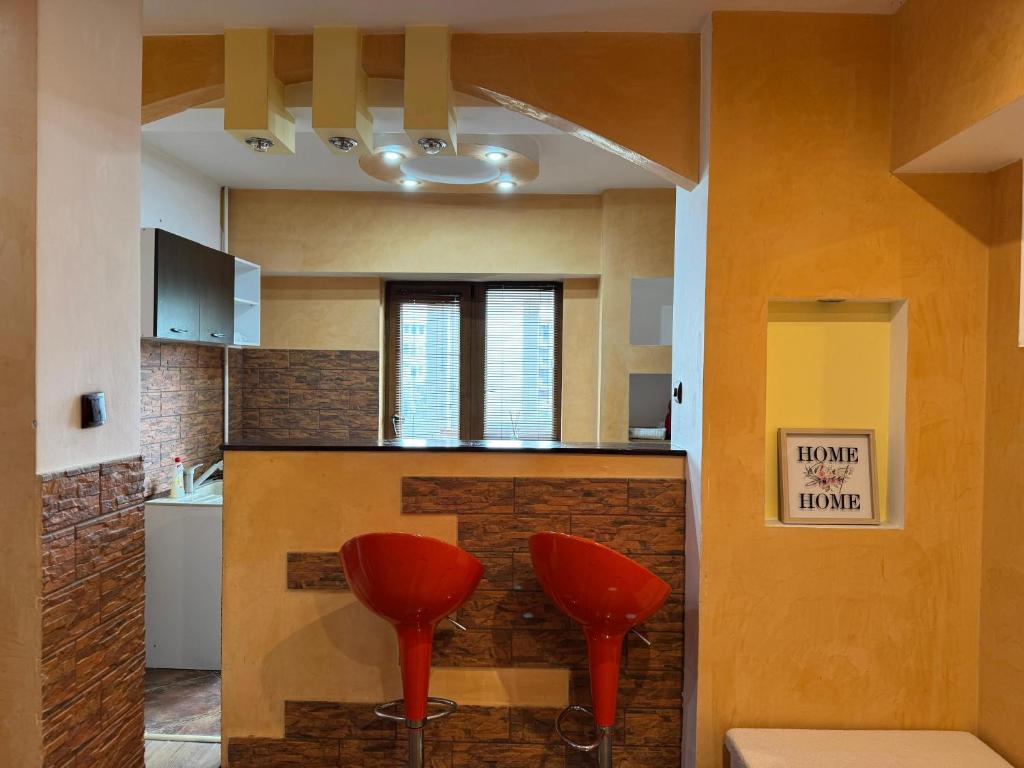 Una cocina con dos taburetes rojos en un mostrador. en Central Lovely Apartment Craiova, en Craiova