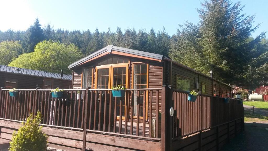 a wooden cabin with windows and a fence at Jasper Lodge in Beautiful Glendevon Country Park Perthshire Scotland in Glendevon