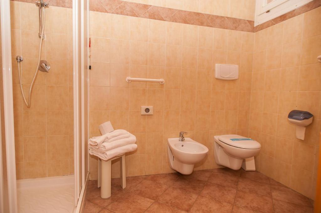 a bathroom with a shower and a toilet and a sink at Hotel Vittoria in Riva del Garda