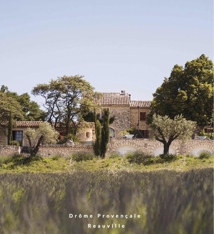 un vieux bâtiment en pierre avec des arbres dans un champ dans l'établissement Domaine des Grillons, à Réauville