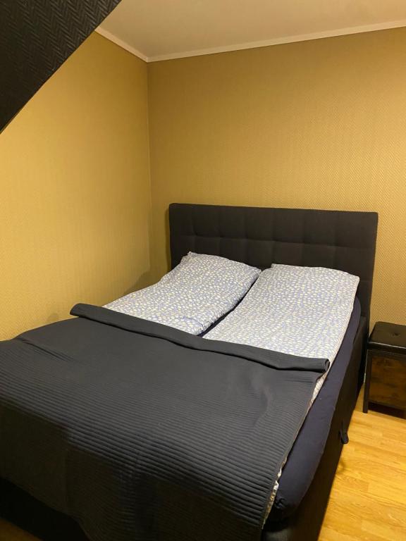a bed with a black headboard in a room at Leilighet med sydvendt balkong in Ålesund