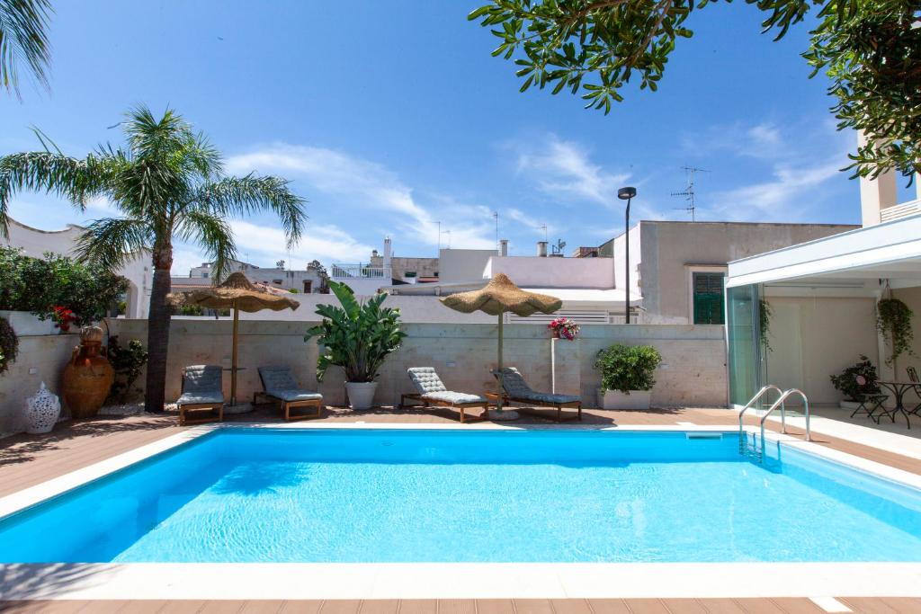a pool with chairs and umbrellas next to a house at Dimora Nesea in Cozze