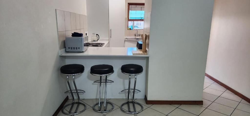 a kitchen with a counter with three stools at Leonella Luxury Apartment in Northwold