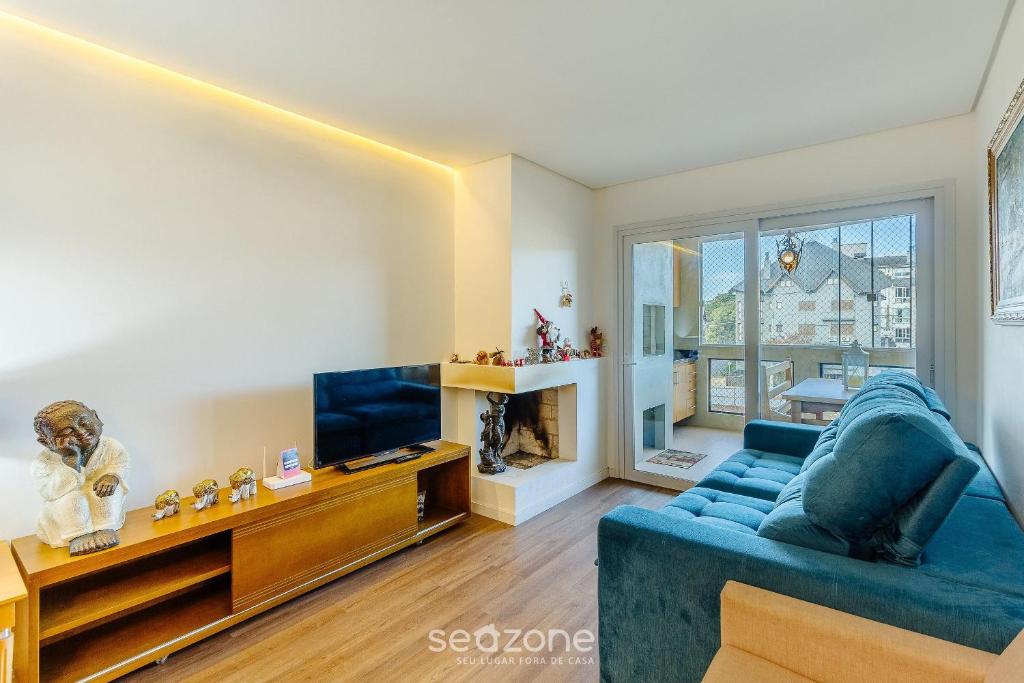 ein Wohnzimmer mit einem blauen Sofa und einem Fernseher in der Unterkunft Apto em Canela de frente ao lago dos patos CBL307 in Canela