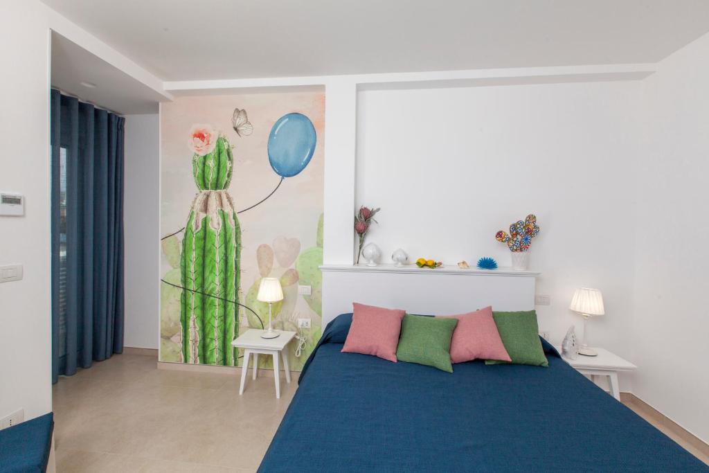 a bedroom with a blue bed with pink and green pillows at Dimora Nesea in Cozze
