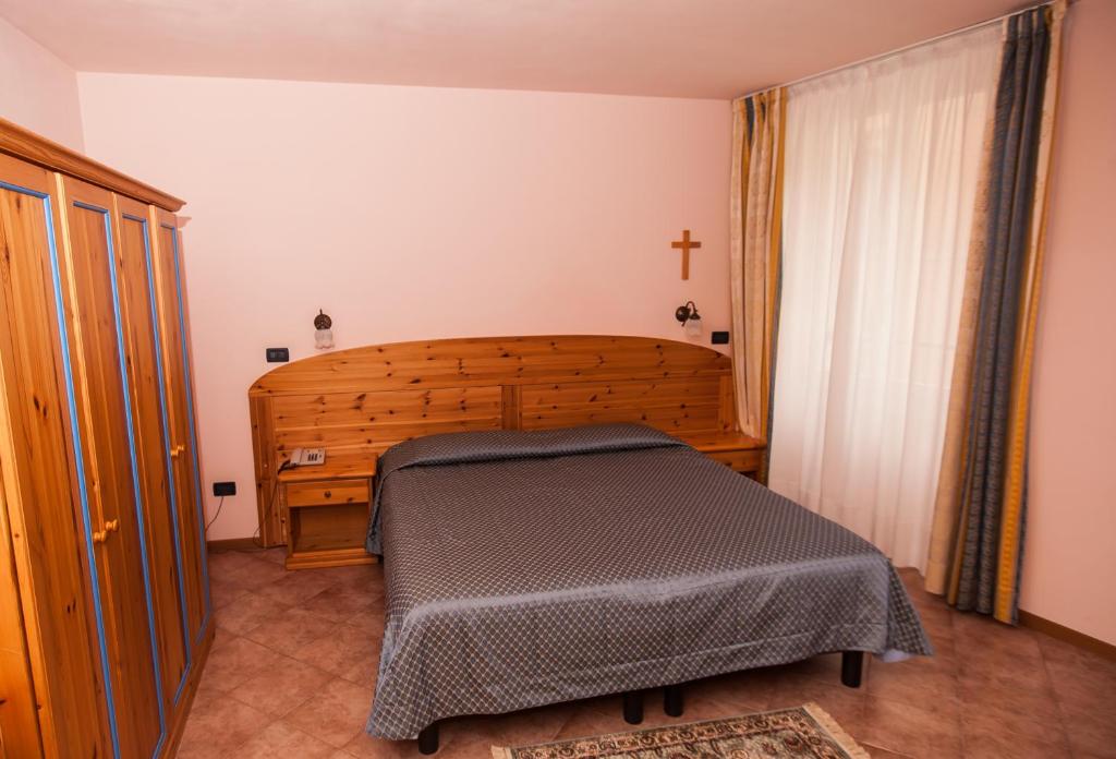 a bedroom with a bed and a cross on the wall at Hotel Vittoria in Riva del Garda