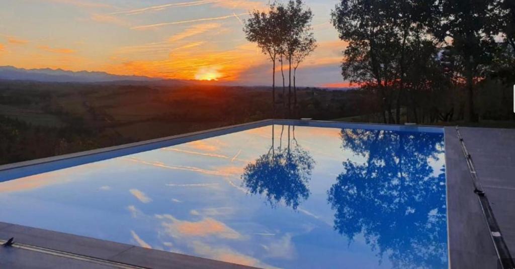 une piscine avec un coucher de soleil en arrière-plan dans l'établissement Villa les chênes, à Unzent