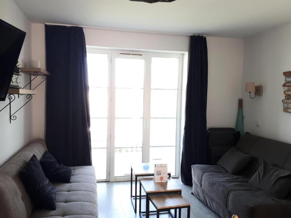 un salon avec un canapé et une grande fenêtre dans l'établissement Port du Crouesty Cap'Océan - maeva Home - Appartement 2 pièces 4 personnes - Sélection - vue sur le Port MAE-1316, à Arzon