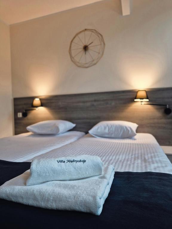 two beds in a hotel room with towels on them at Villa Międzyzdroje in Międzyzdroje