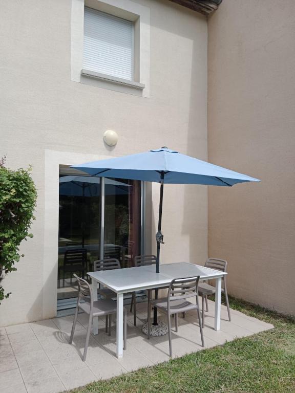 un parasol bleu assis sur une table avec des chaises dans l'établissement Le petit logis de Lascaux, à Montignac