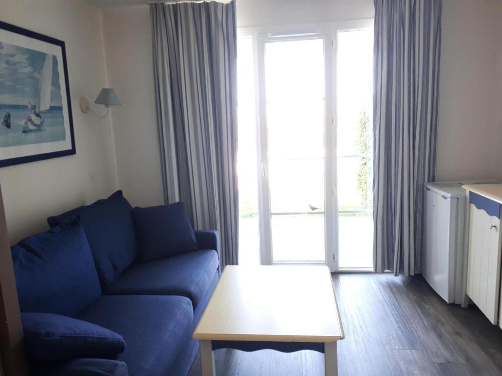 un salon avec un canapé bleu et une table dans l'établissement Port du Crouesty Cap'Océan - maeva Home - Appartement 2 pièces 4 personnes - Sélection MAE-4534, à Arzon