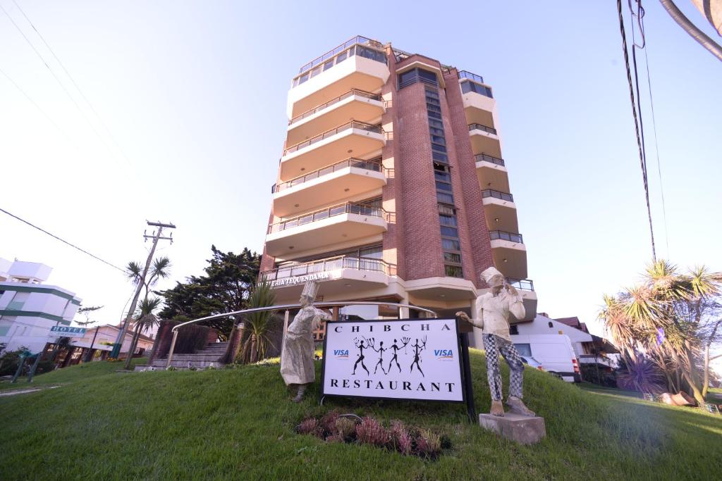un cartel en la hierba frente a un edificio de la Hostería Tequendama Classic & Resort en Villa Gesell