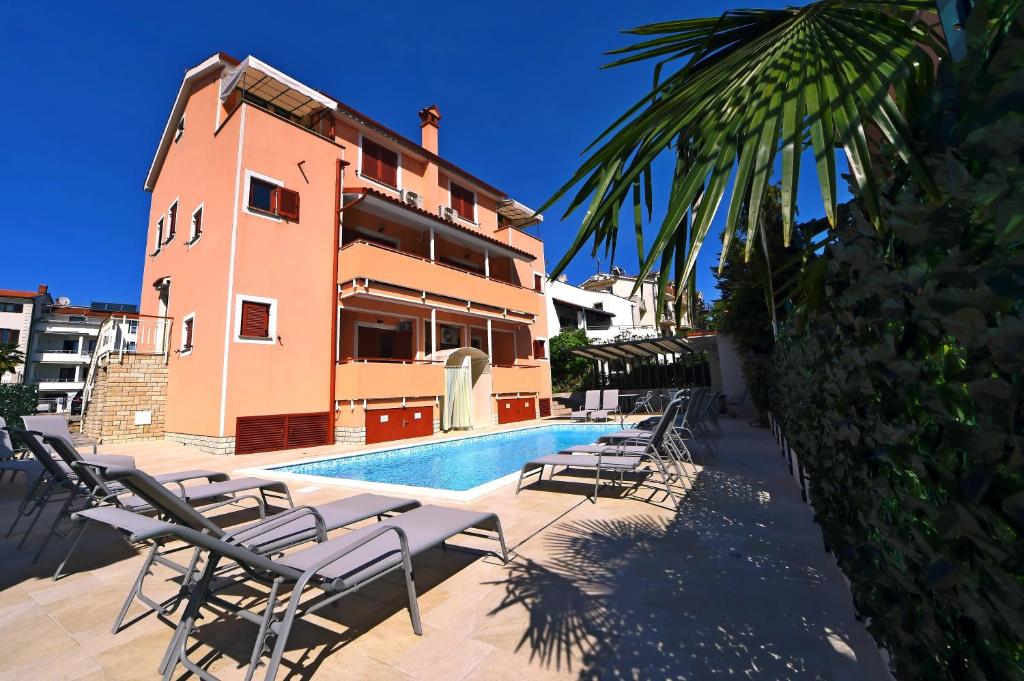 a swimming pool with lounge chairs next to a building at Apartments Zdjelar in Poreč