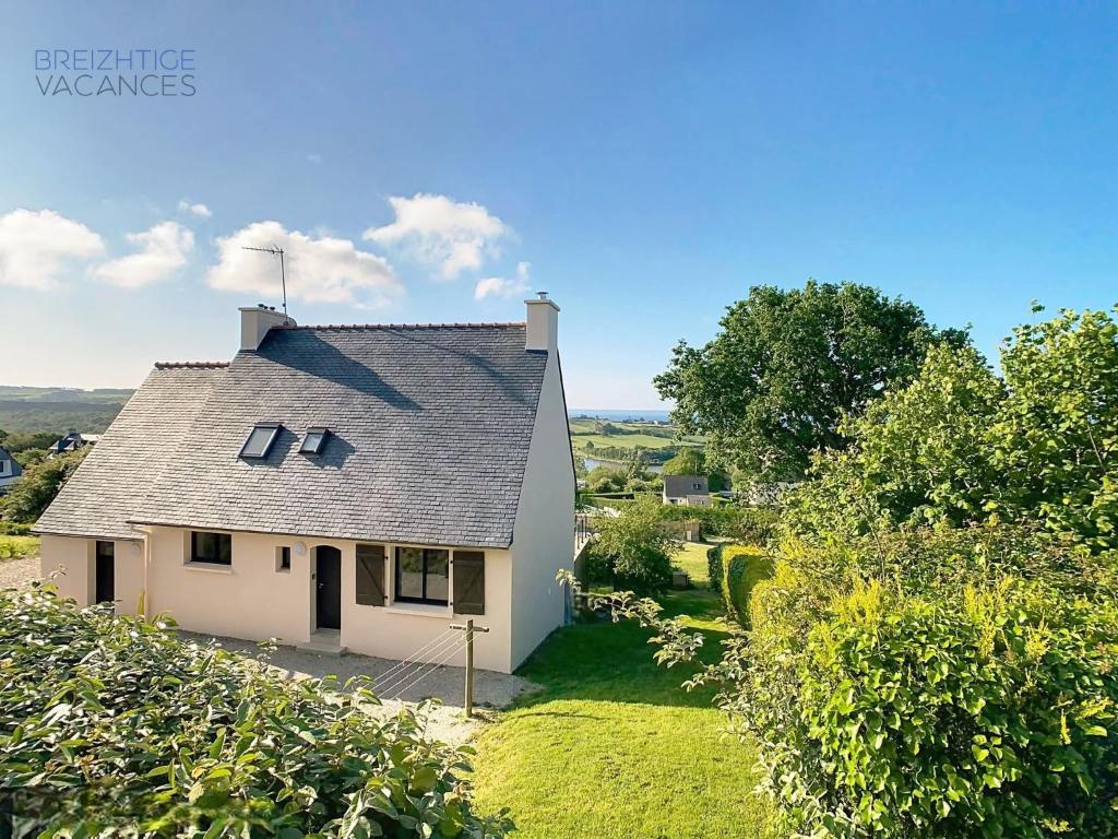 une petite maison blanche sur une colline avec des arbres dans l'établissement Maison Anémone - Vue mer - Crozon, Bretagne, à Crozon