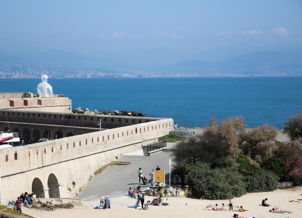 Un groupe de personnes debout sur un mur à côté de l'océan dans l'établissement 3BR on the Remparts of Antibes - Sea & Mountain View, à Antibes