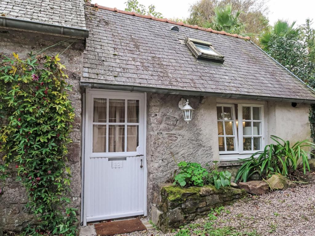 une petite maison en pierre avec une porte et des fenêtres blanches dans l'établissement Holiday Home Gwenn Tiny House by Interhome, à Paimpol