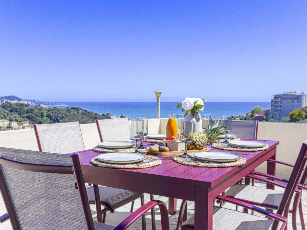 a wooden table with plates of food and the ocean at Holiday Home Villa la Bergerie by Interhome in Nice