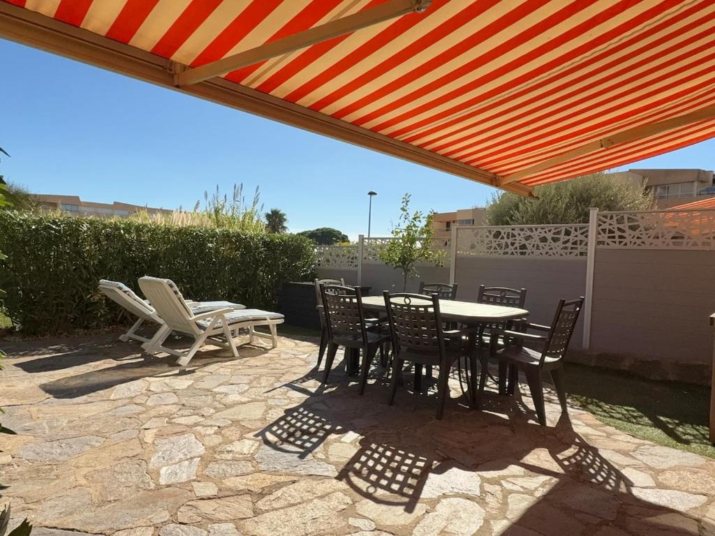 d'une terrasse avec une table et des chaises sous un parasol orange. dans l'établissement L'ivoire classed 2étoiles pied dans l'eau, à La Londe-les-Maures