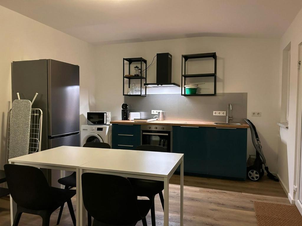 a kitchen with a table and chairs and a refrigerator at Modernes 1-Zimmer Apartment mit 2 Einzelbetten in Offenbach bei Frankfurt in Offenbach