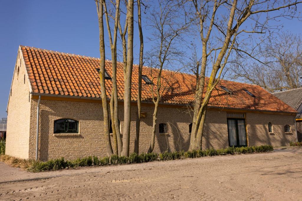 Una casa de ladrillo con techo rojo y algunos árboles. en De Lierhand, en Lier