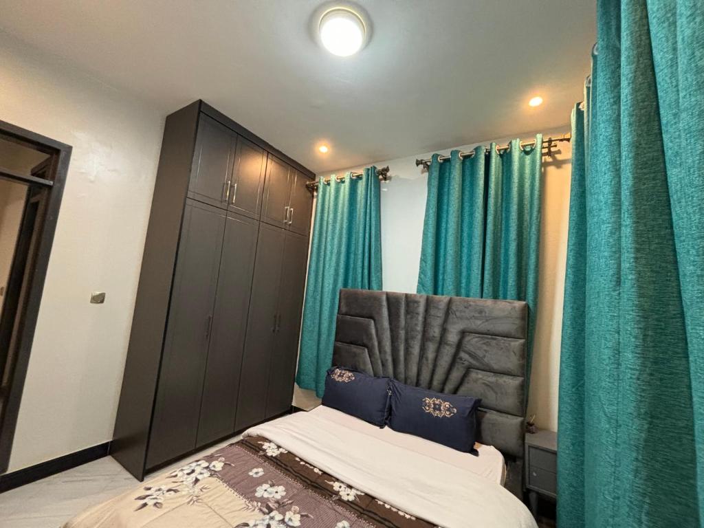 a bedroom with a bed and a green curtain at Faiths Furnished Apartments in Kampala