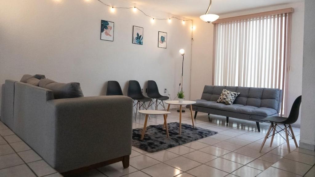 Una sala de estar con un sofá, una mesa y sillas. en Casa céntrica para grupos grandes, en San Luis Potosí