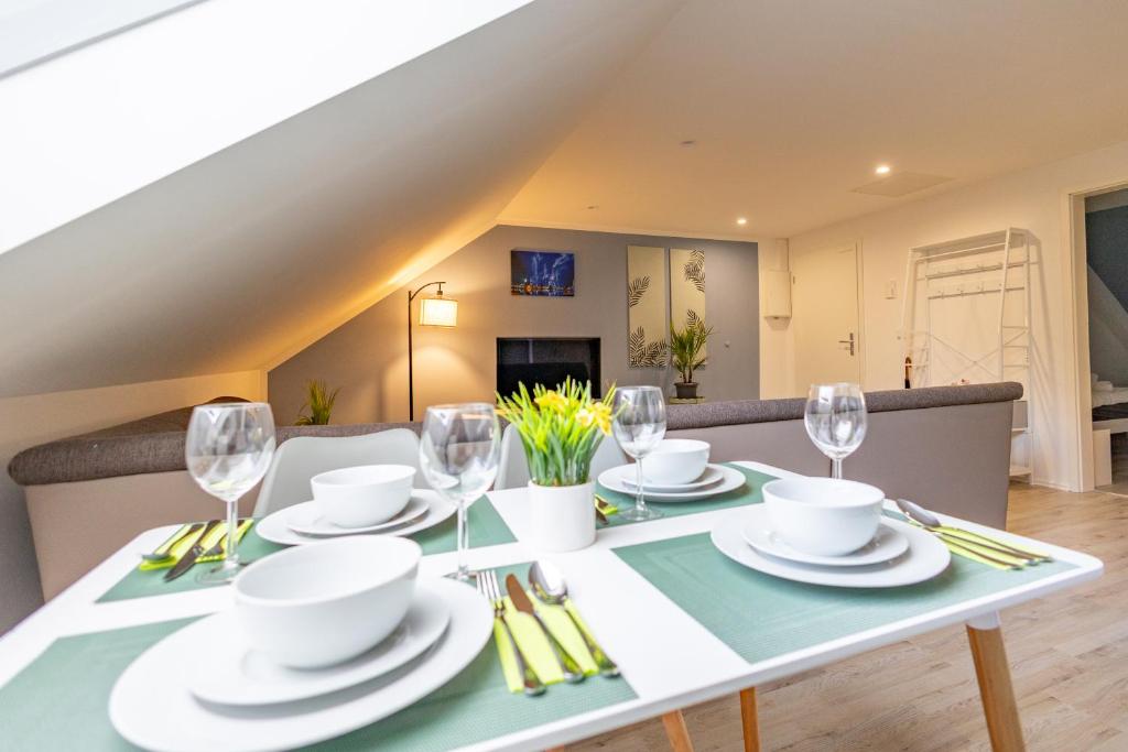 a dining room table with plates and wine glasses at HANNIBAL - City Apartment "T-Roc", VW Nähe, Parkplatz, City Nähe, Küche, HighSpeed-WLAN in Wolfsburg