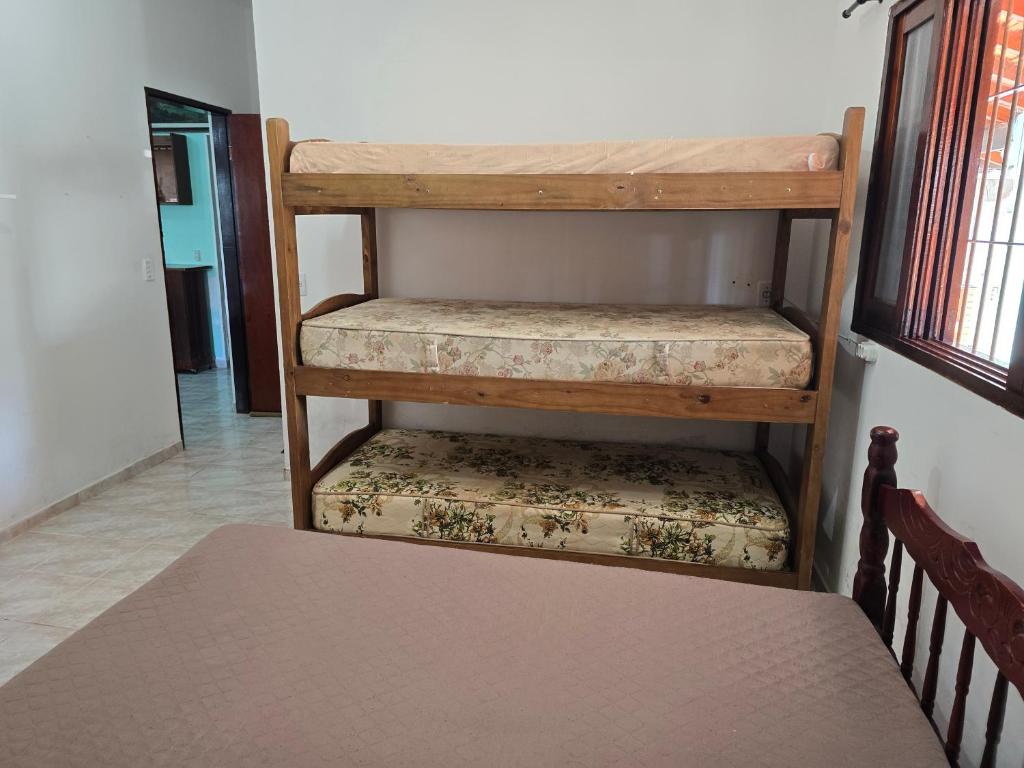 a room with a bunk bed and a wooden shelf at Recanto feliz in Peruíbe