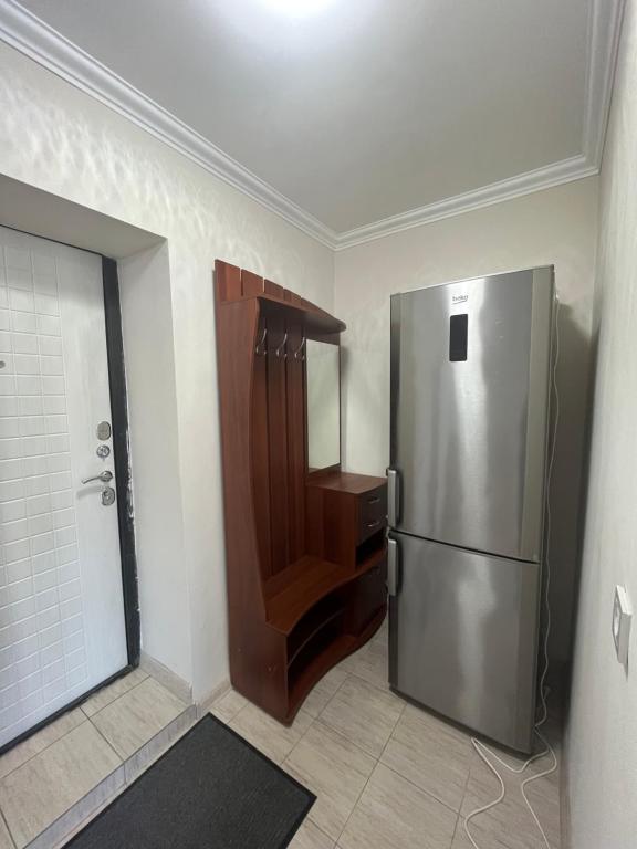 a kitchen with a stainless steel refrigerator in a room at Уютная квартира-студия в курортной зоне Щучинский in Uchitelʼ